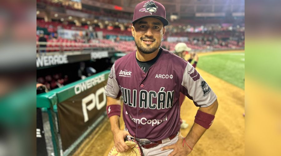 Jugador de beisbol portando uniforme en colores guinda y gris con gorra y sosteniendo una manopla, en un estadio