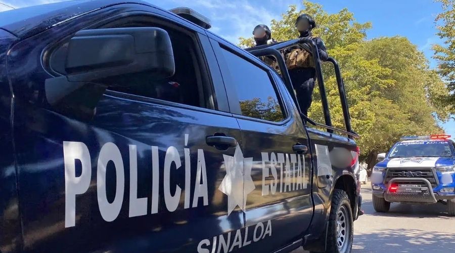 Unidad de la Policía Estatal con dos elementos en la parte trasera, además de una patrulla de policía municipal