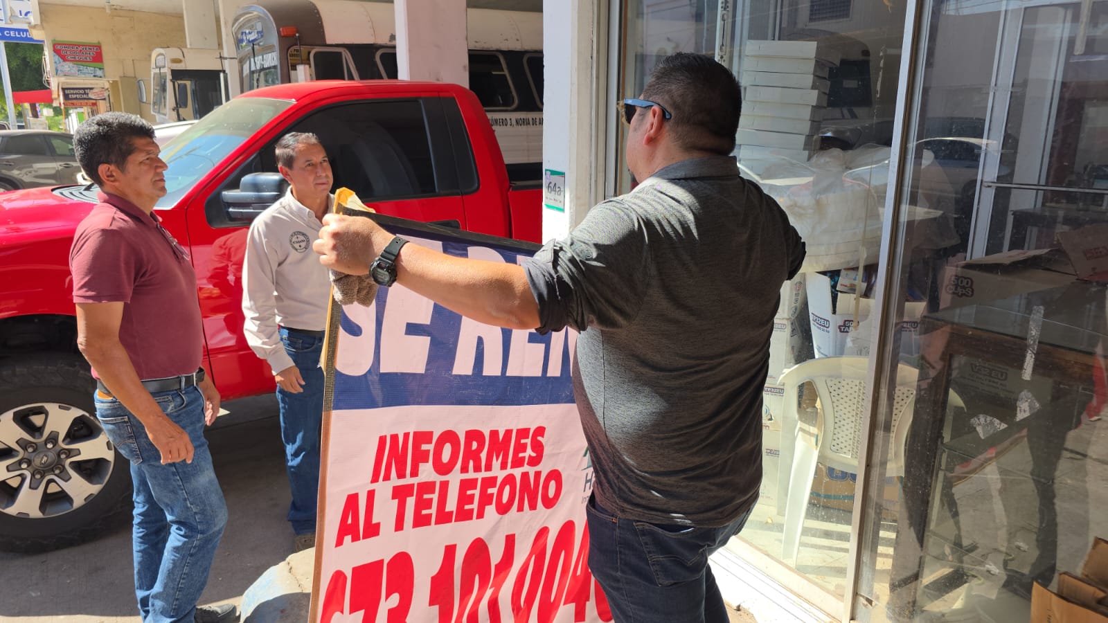 Tres personas con una lona que dice se renta en el mercado municipal de Guamúchil