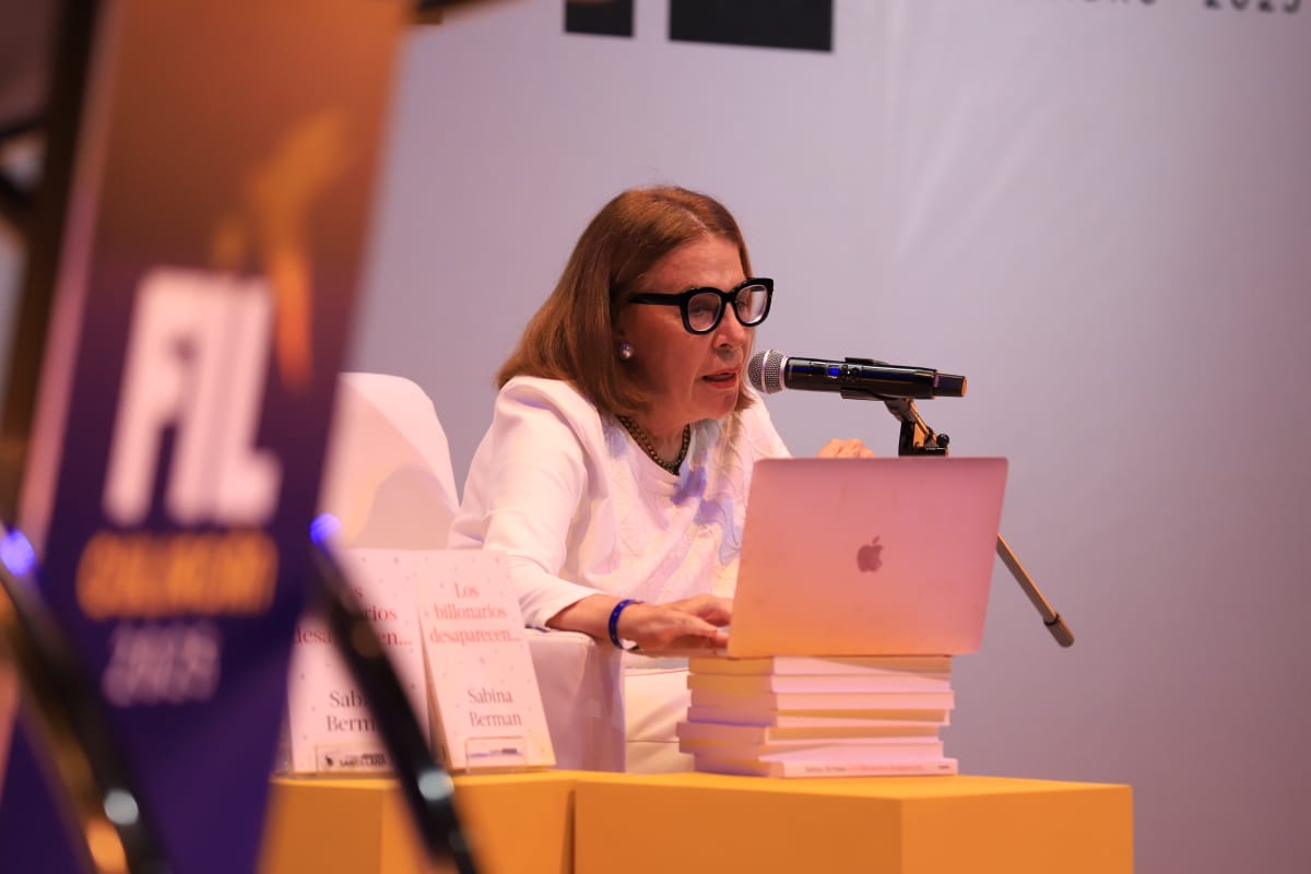Sabina Berman sentada junto a laptop y micrófono