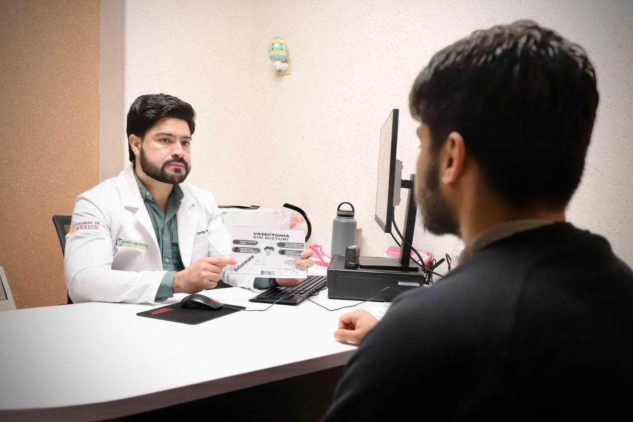 Un doctor en su consultorio junto a un paciente de espaldas