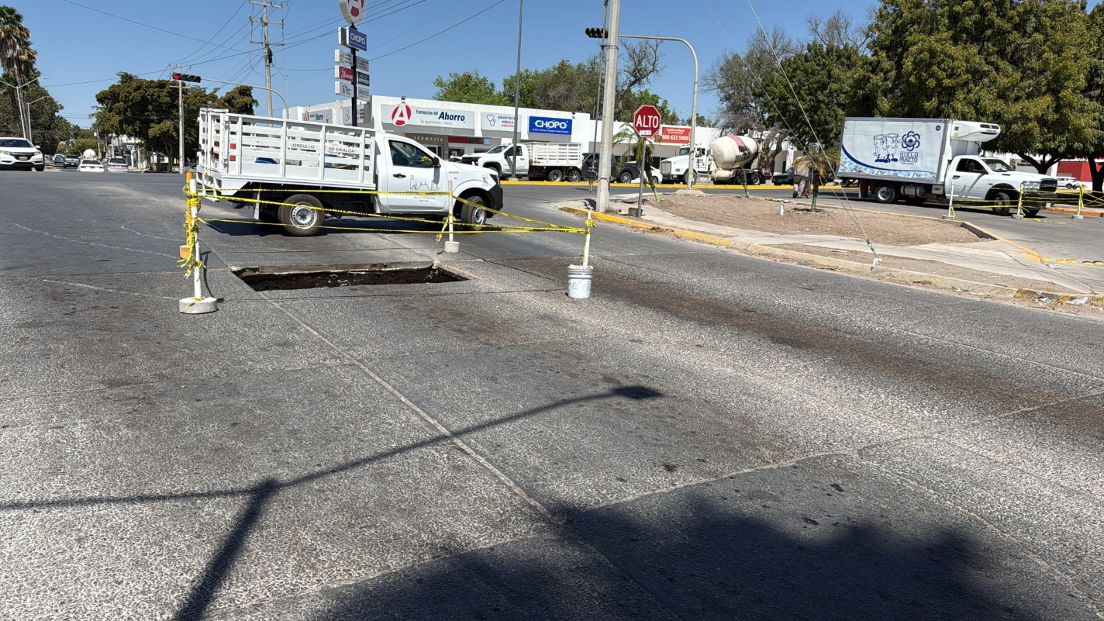Calle de Los Mochis con un socavón rodeado de cinta amarilla de precaución