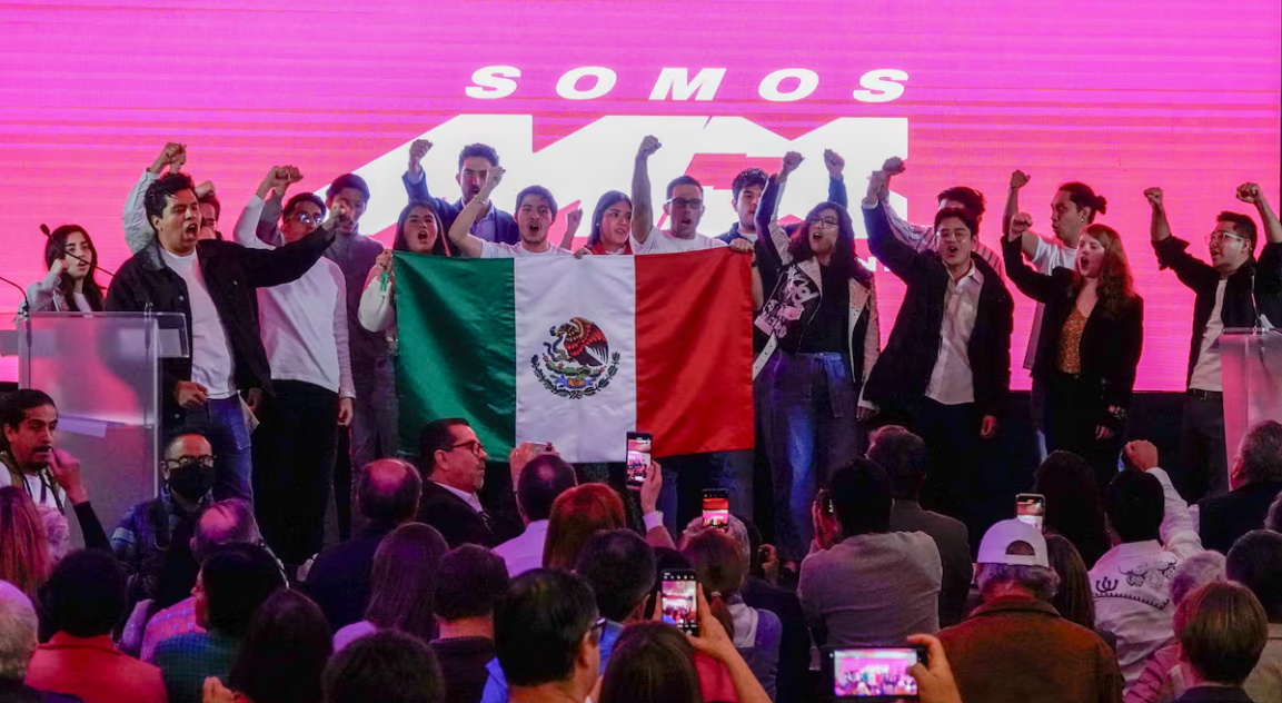 Integrantes del partido Somos México arriba de un escenario sosteniendo la bandera mexicana
