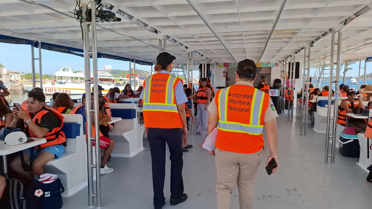 Personas de supervisión con chaleco naranja con líneas amarillas en un catamarán