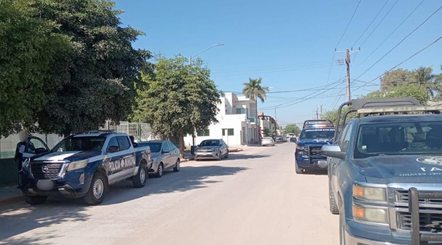 Tres unidades de seguridad estacionadas en una calle de Guasave. dos elementos de la policía municipal debajo de su unidad