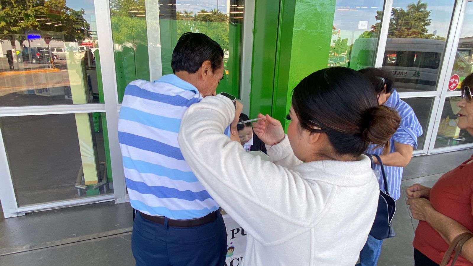 Señor con playera de rayas azules y blancas aplicándole una vacuna en Ahome