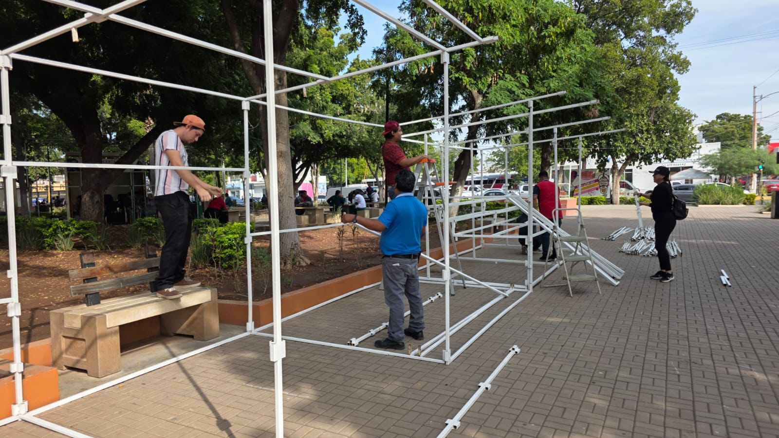 Personas poniendo tubos de fierro en la plazuela