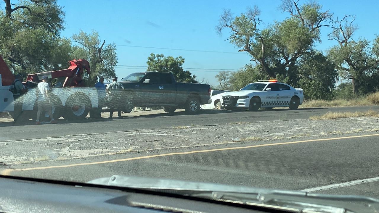Camioneta siendo levantada por una grúa por un choque contra muro de contención, hay una unidad de la Guardia Nacional