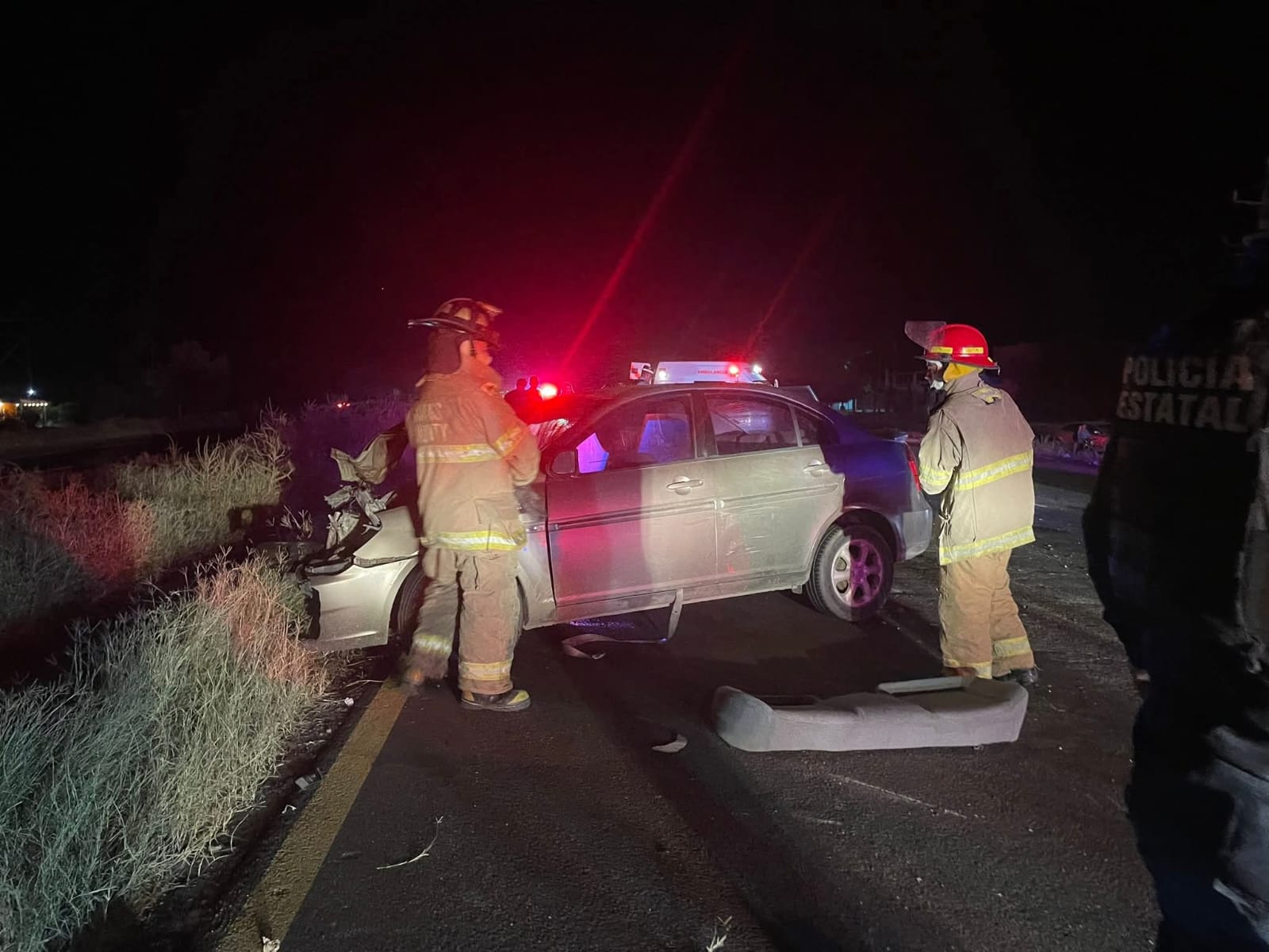 Elementos del cuerpo de bomberos frente a un automóvil que acaba de sufrir un accidente