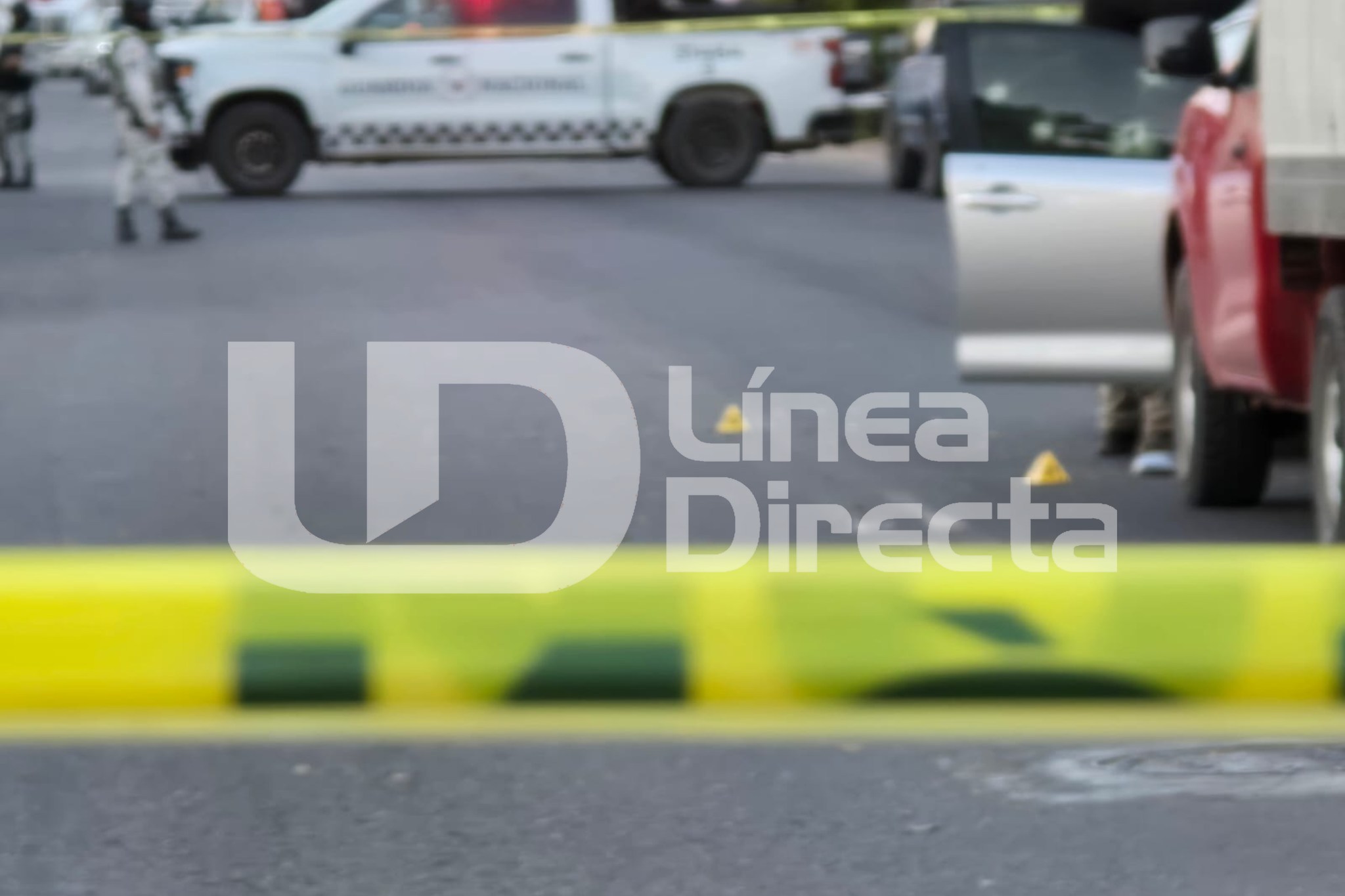 Cinta amarilla de precaución en una escena del crimen, al fondo se observan elementos de la Guardia Nacional junto a una unidad de la corporación