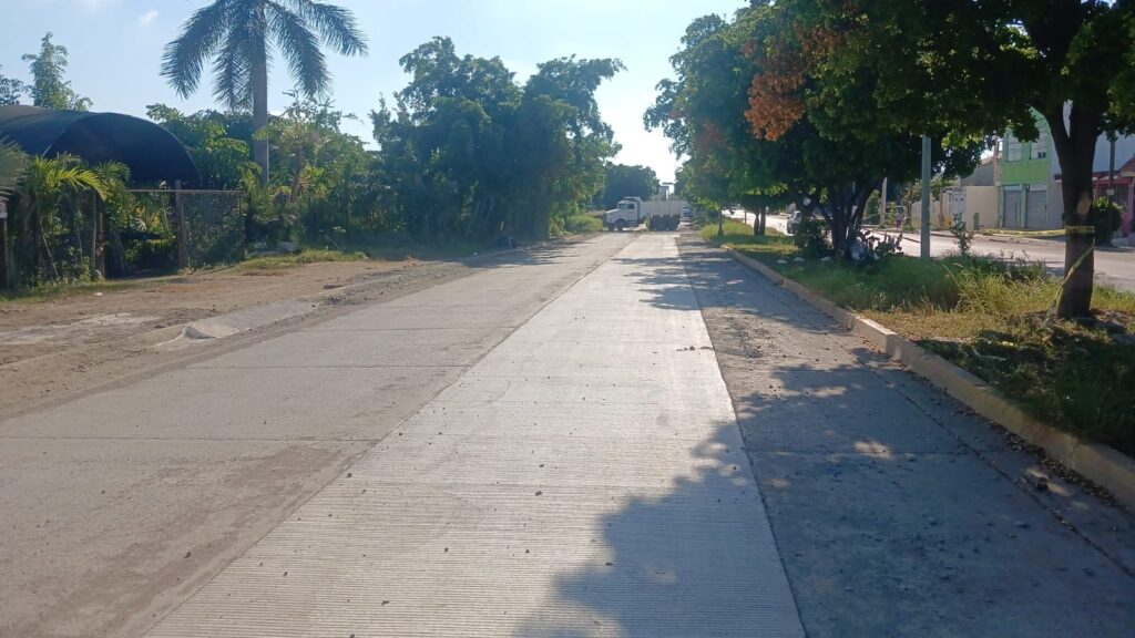 calle pavimentada en Culiacán, a los lados se observa terracería y algunos árboles
