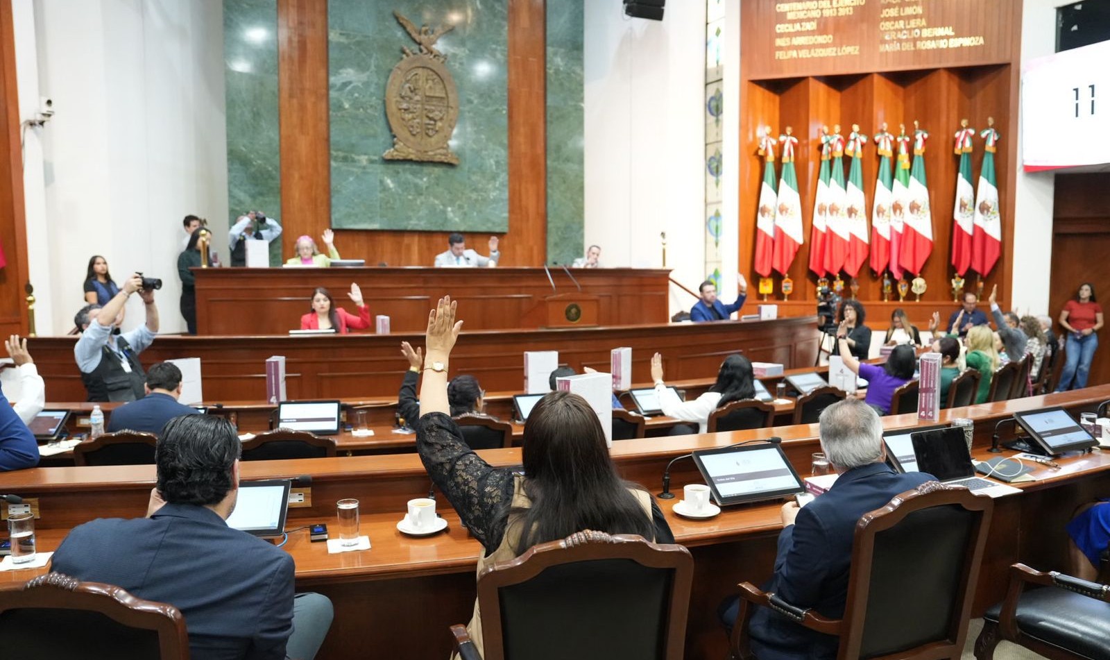 Personas levantando la mano en el Congreso del Estado durante una sesión