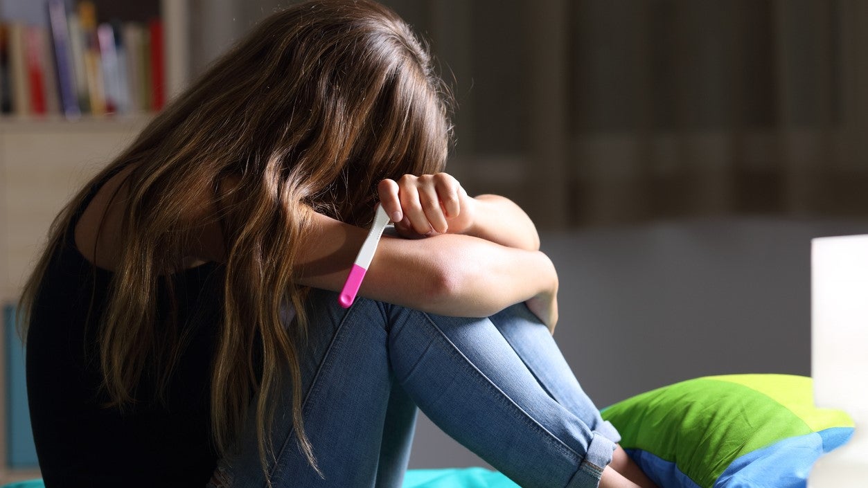 Adolescente con prueba de embarazo en mano