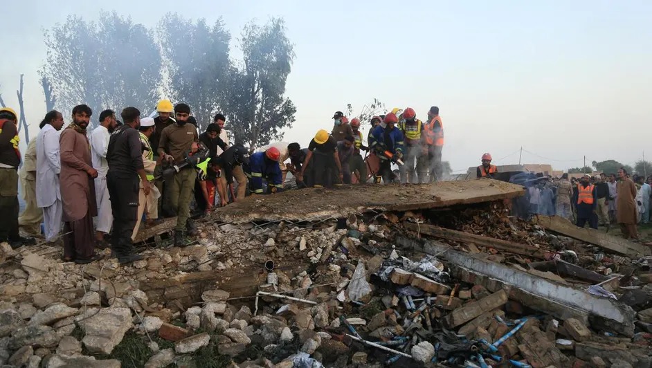 Personas están paradas cerca de los rastro de la explosión en Pakistán