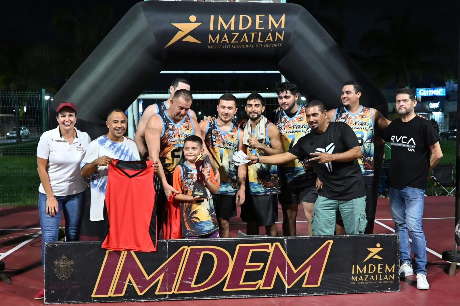 Personas con uniformes deportivos sosteniendo un trofeo y premio de dinero