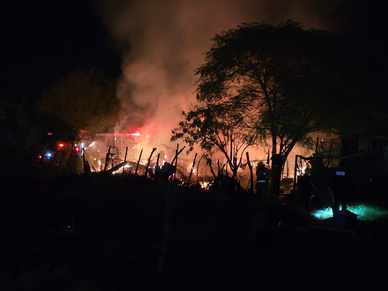 fotografía tomada de alto contraste de casas de madera siendo incendiadas, rodeadas en llama, esto en Los Mochis