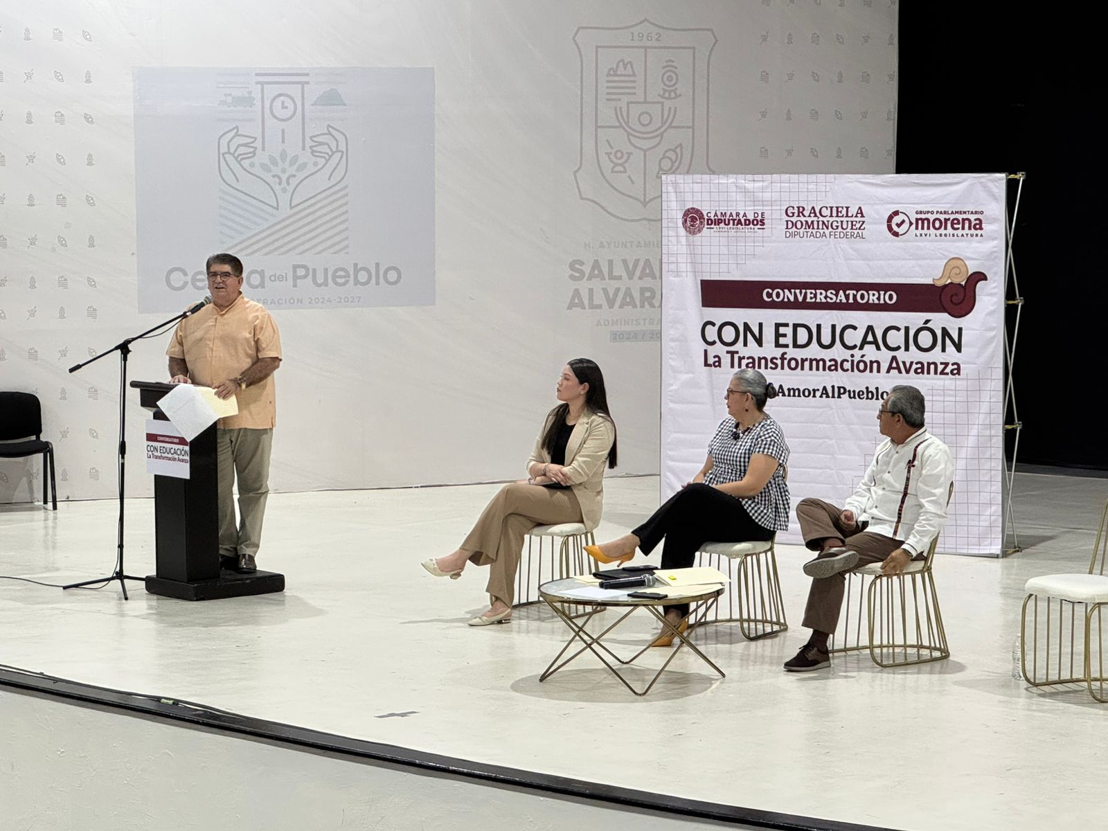 Cuatro personas tres sentadas y una de pie en un foro sobre educacion