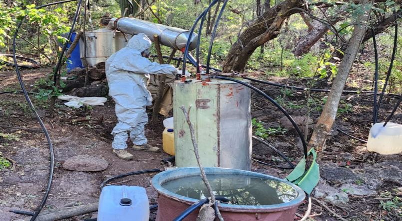 Hombre con equipo especializado para la destrucción de productos químicos, junto con artefactos y tambos para la producción de droga en Culiacán