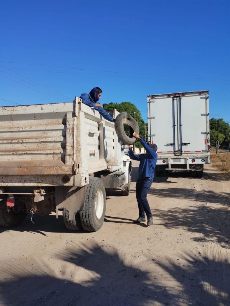 Hombre pasándole una llanta a otro hombre