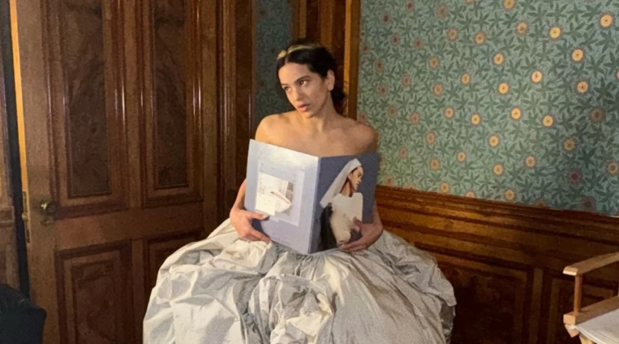 La cantante Rosalía sentada en una silla y sostenido un álbum
