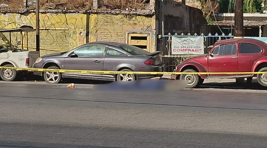Cinta amarilla de precaución delimitando la zona dónde hay un cádaver en el suelo de una calle y hay carros