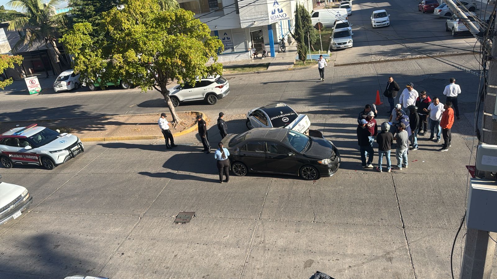 En el centro de la calle justo en el retorno, dos autos colisionados, alrededor personas involucradas en el accidente y autoridades de transito