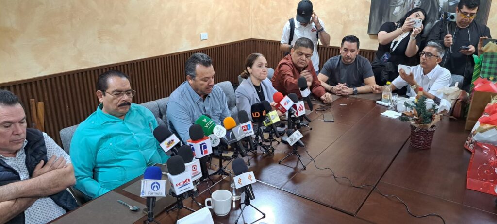 Personas en conferencia de prensa junto a micrófonos de medios de comunicación