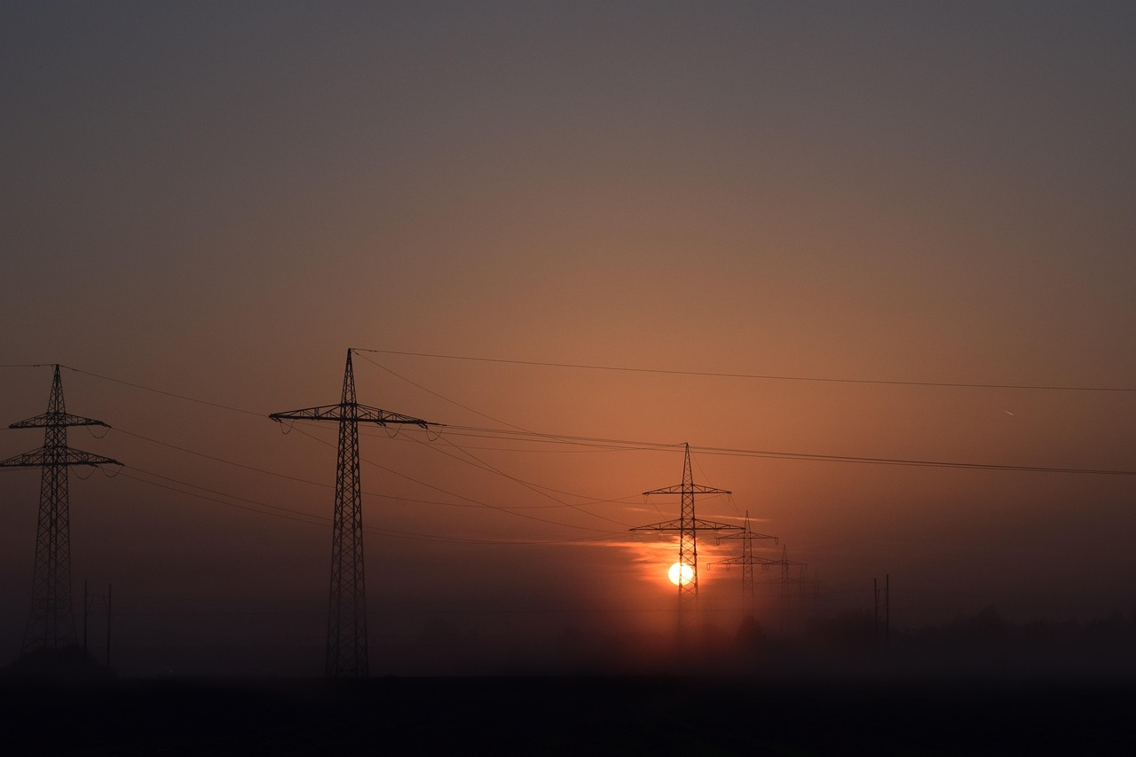 Paisaje de amanecer con el sol saliendo y se observan torres de electricidad