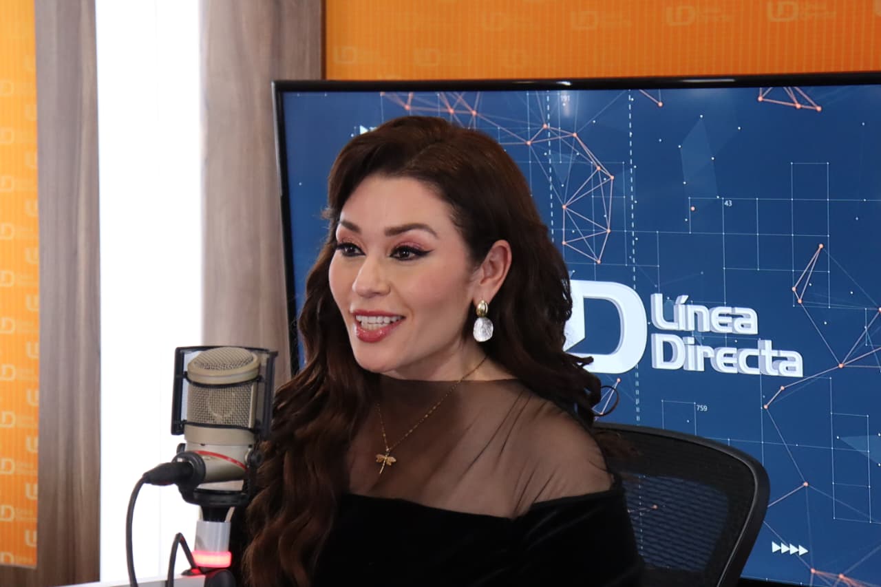 Mujer viendo hacia un lado sonriendo frente a un micrófono en un estudio de grabación