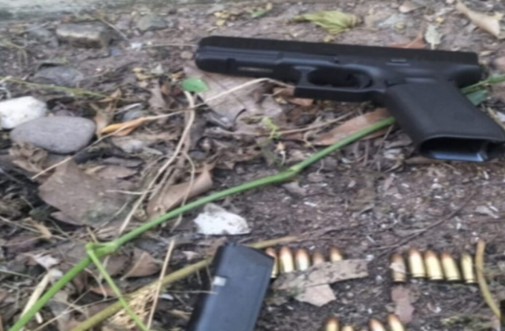 Pistola con balas y un cartucho tirados en la tierra