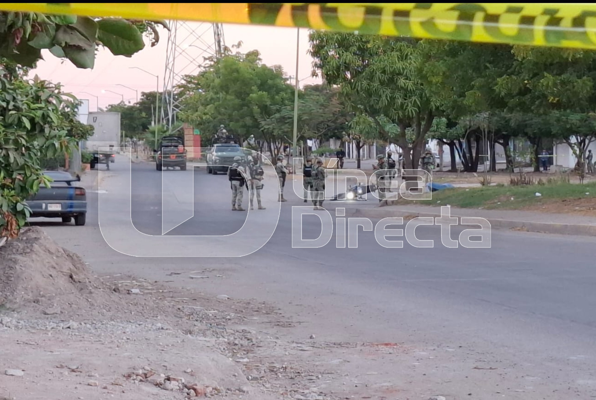 Cinta amarilla de precaución y al fondo se observan elementos del Ejercito Mexicano en una calle
