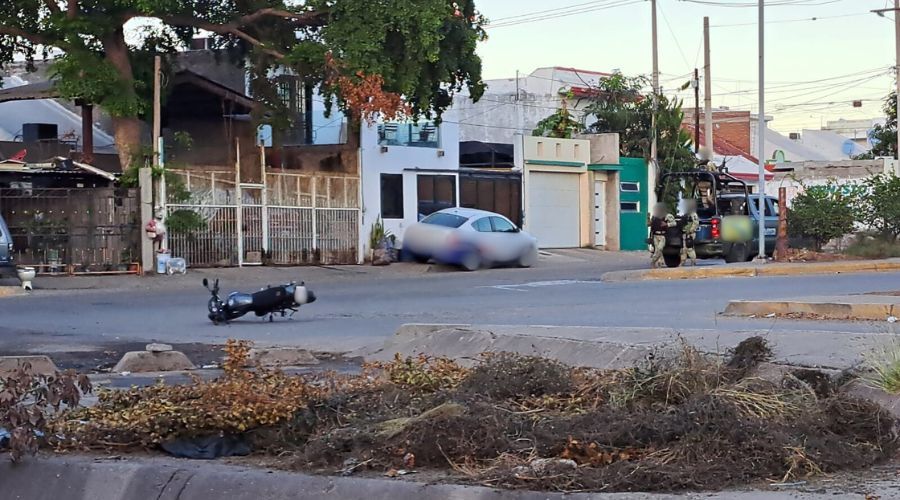 Motocicleta tirada en una calle y una unidad del Ejército Mexicano junto a elementos