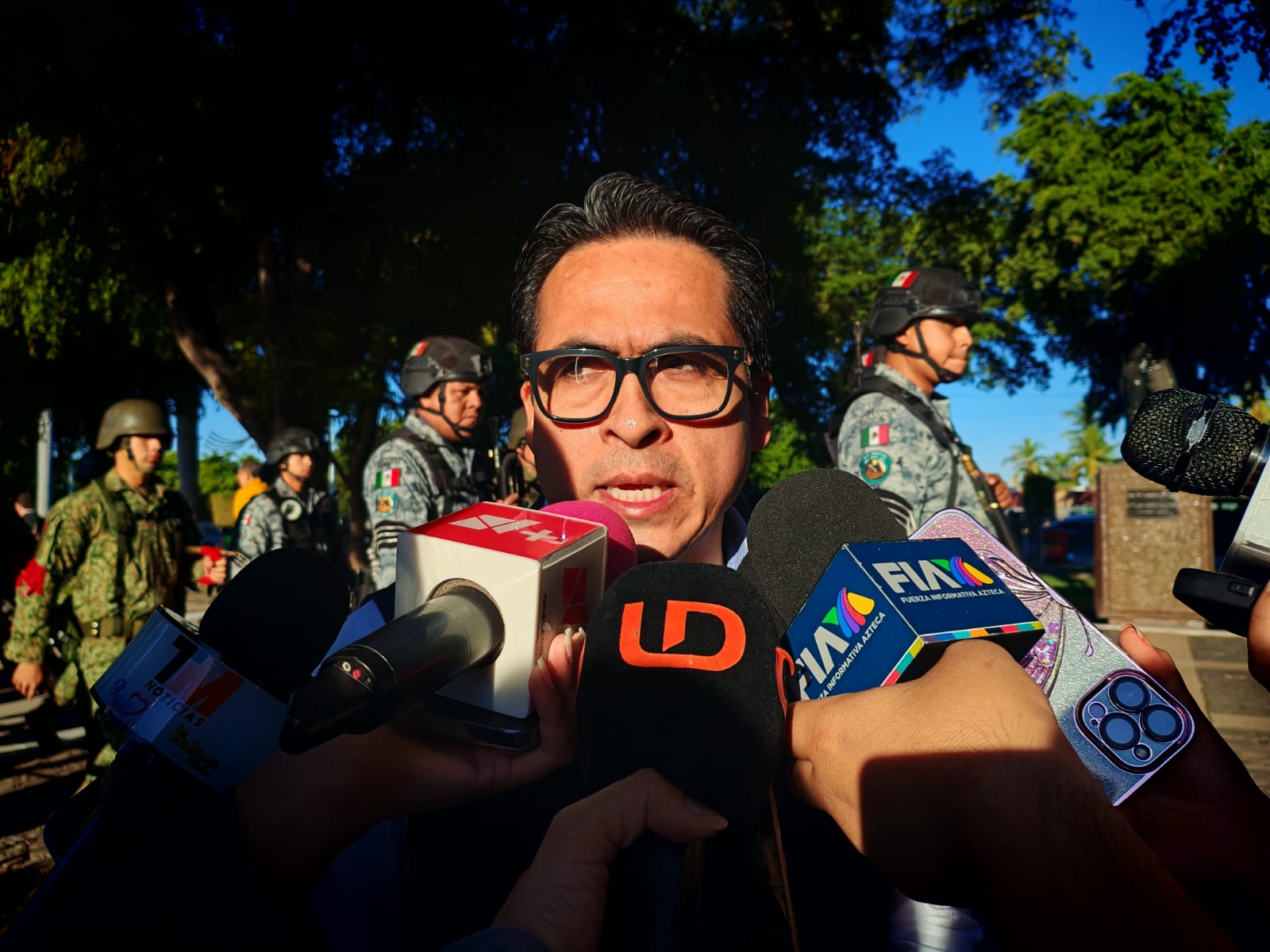 Persona hablando viendo hacia el frente con micrófonos