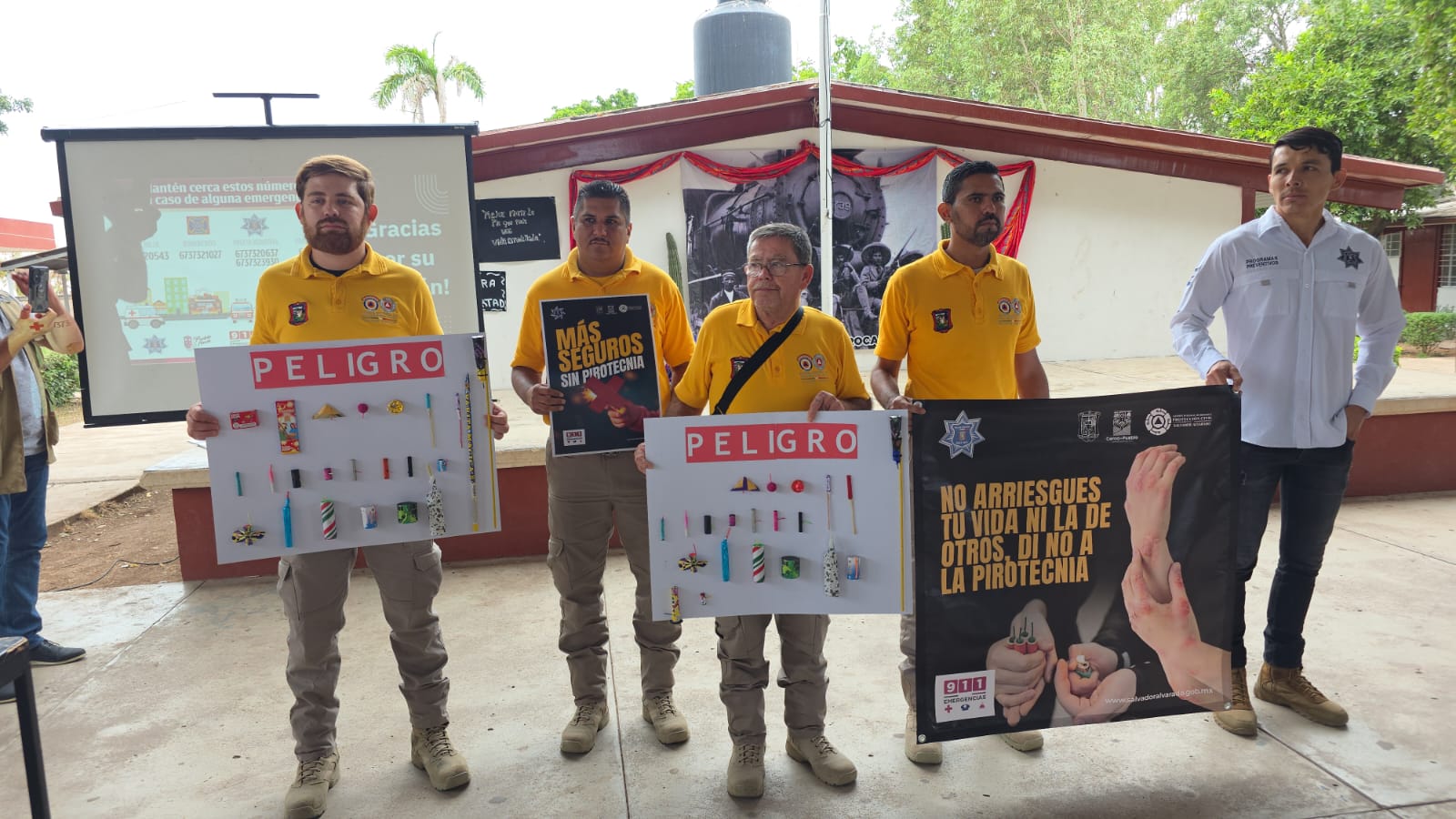 Elementos de protección civil en una escuela de Salvador Alvarado sosteniendo pancartas de prevención contra la pirotecnia