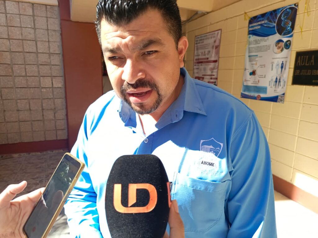 Hombre de camisa azul hablando hacia un micrófono negro con las letras LD en color naranja