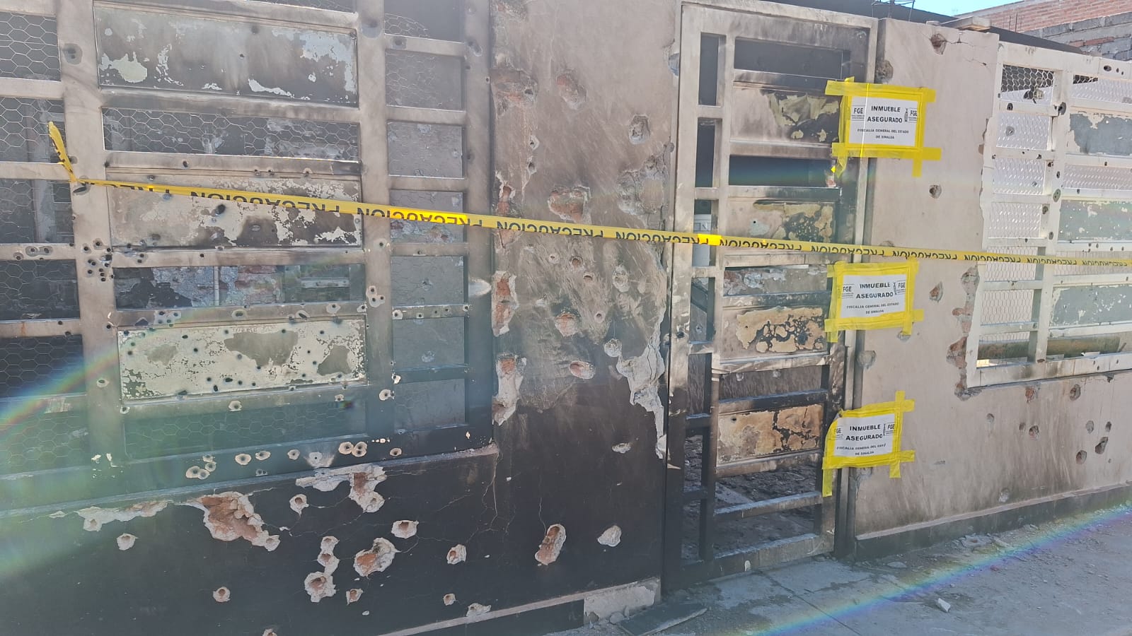 Casa con impactos de bala junto a una cinta amarilla