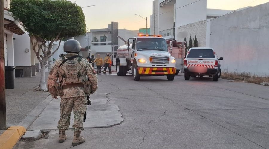 Personal del ejército mexicano de espaldas con camiones de bomberos de fondo