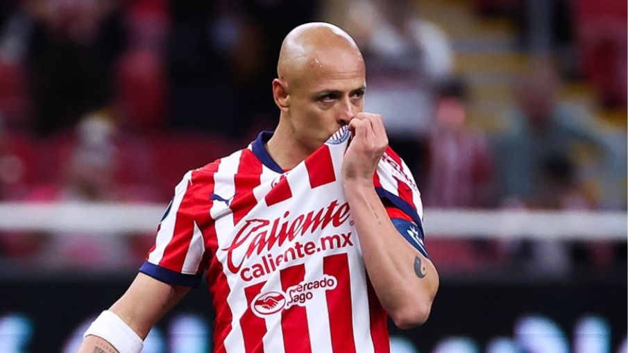 Chicharito Hernández con el uniforme de chivas besando el escudo