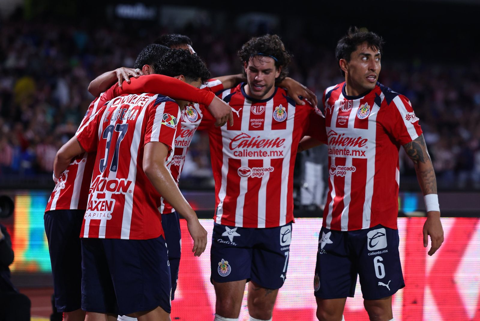 Jugadores de chivas abrazados celebrando un gol