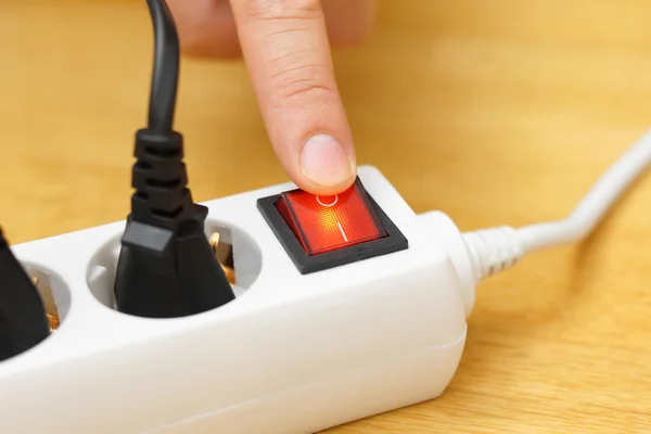 Dedo presionando un botón rojo de un multiconector blanco