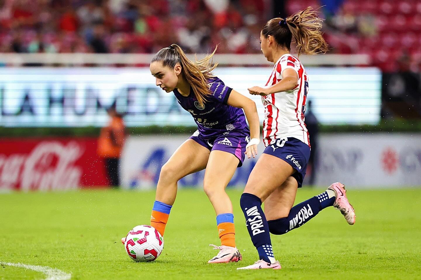 Dos futbolistas femeniles en la disputa del balón
