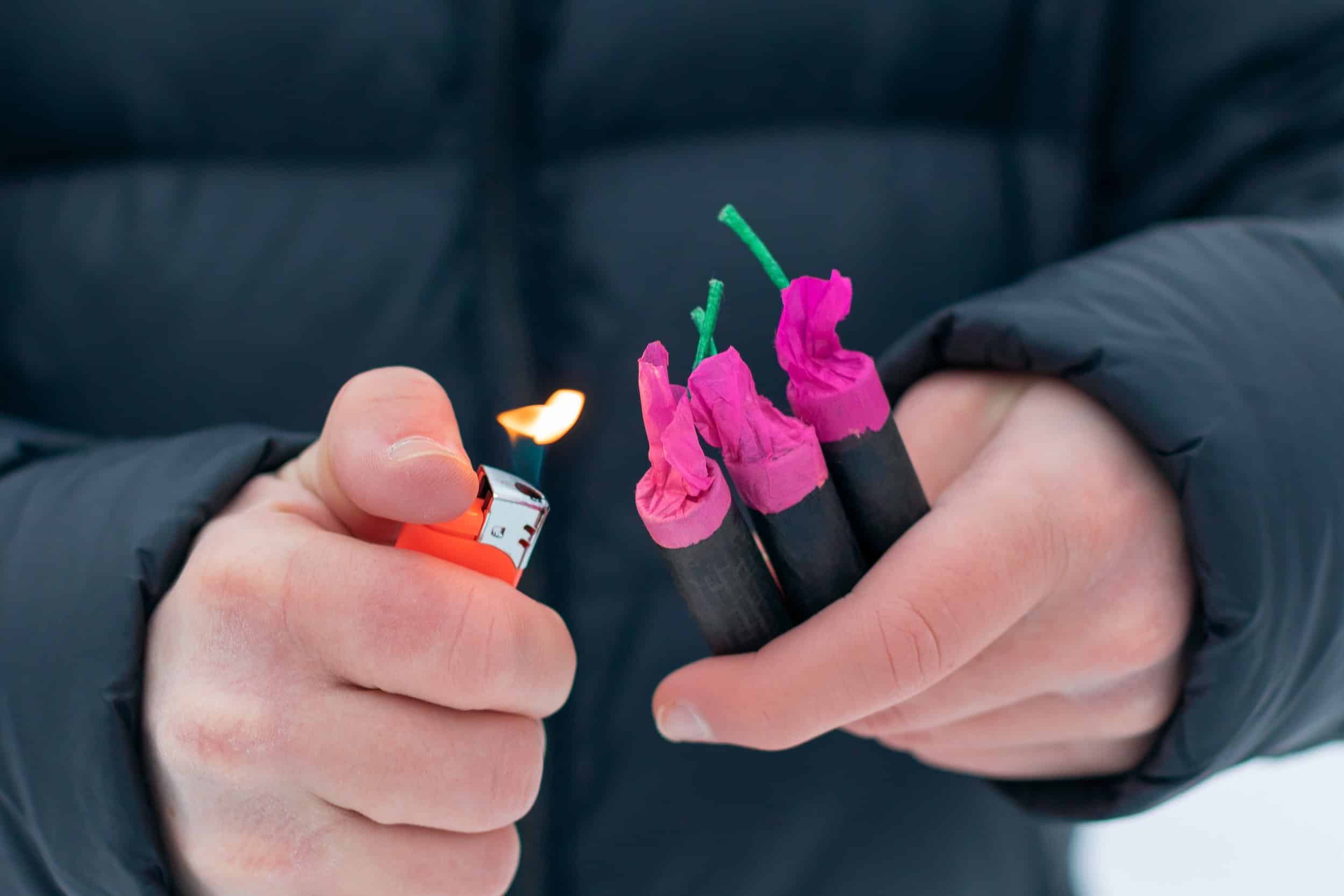 Persona sosteniendo con sus manos pirotecnia y un encendedor