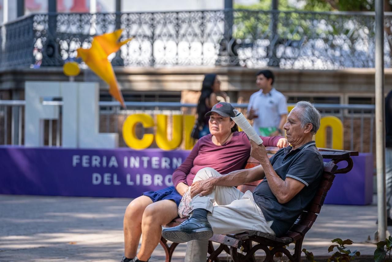 Un señor y una señora sentados en una banca en la Feria Internacional del Libro