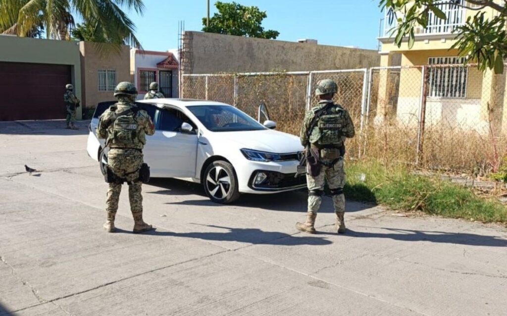 Dos militares parados junto a un carro blanco