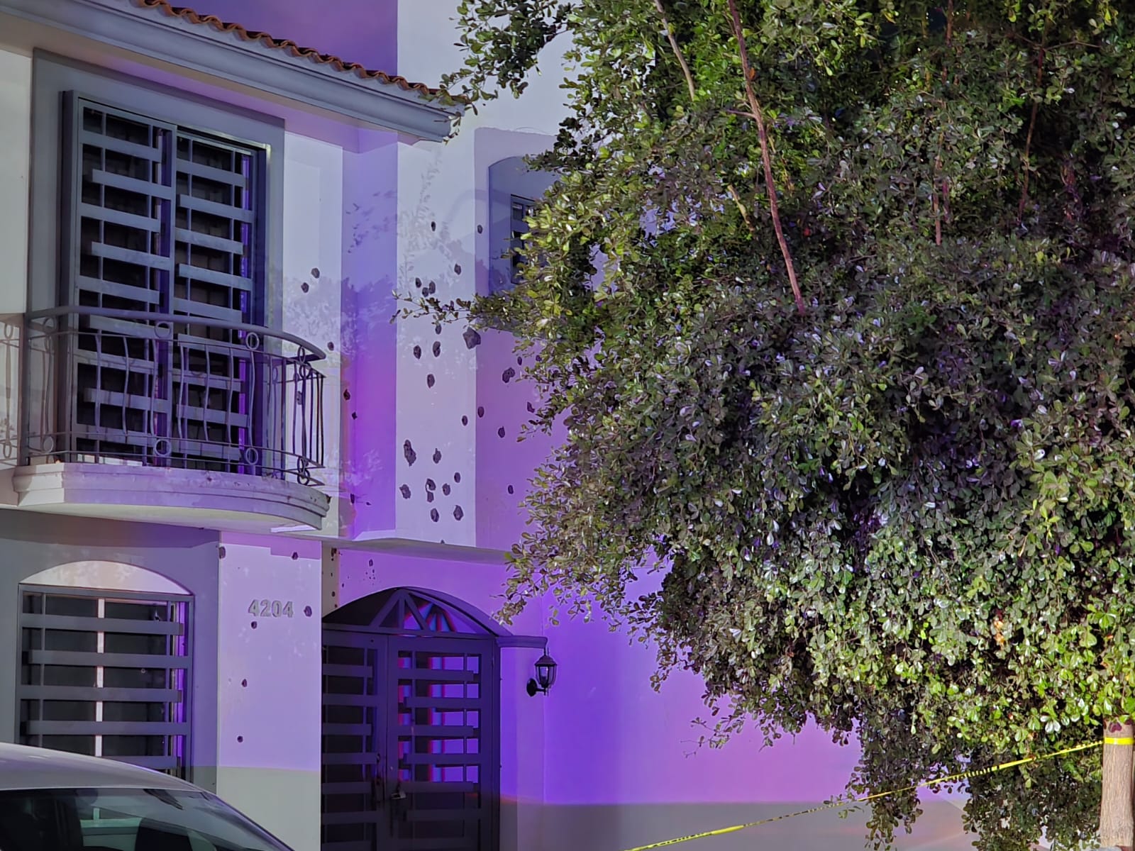 Fachada de casa con impactos de vala y un arbol