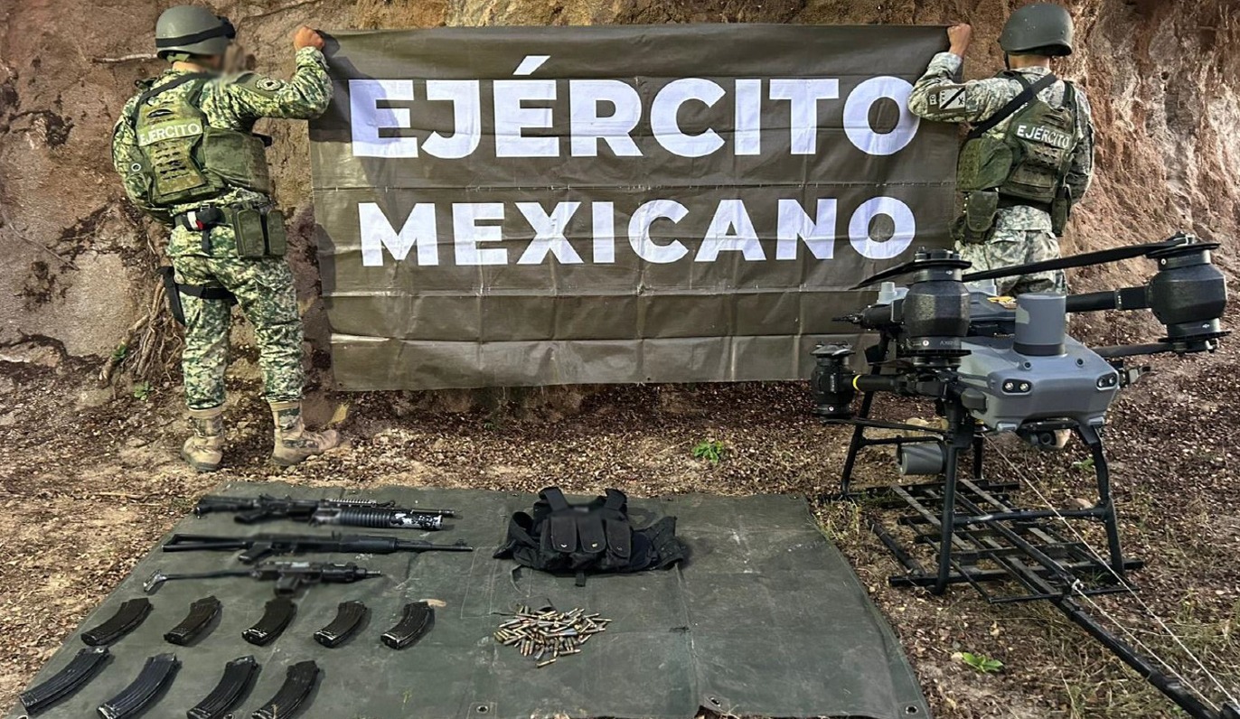 Militares sosteniendo un banner de espaldas y los artefactos asegurados al frente