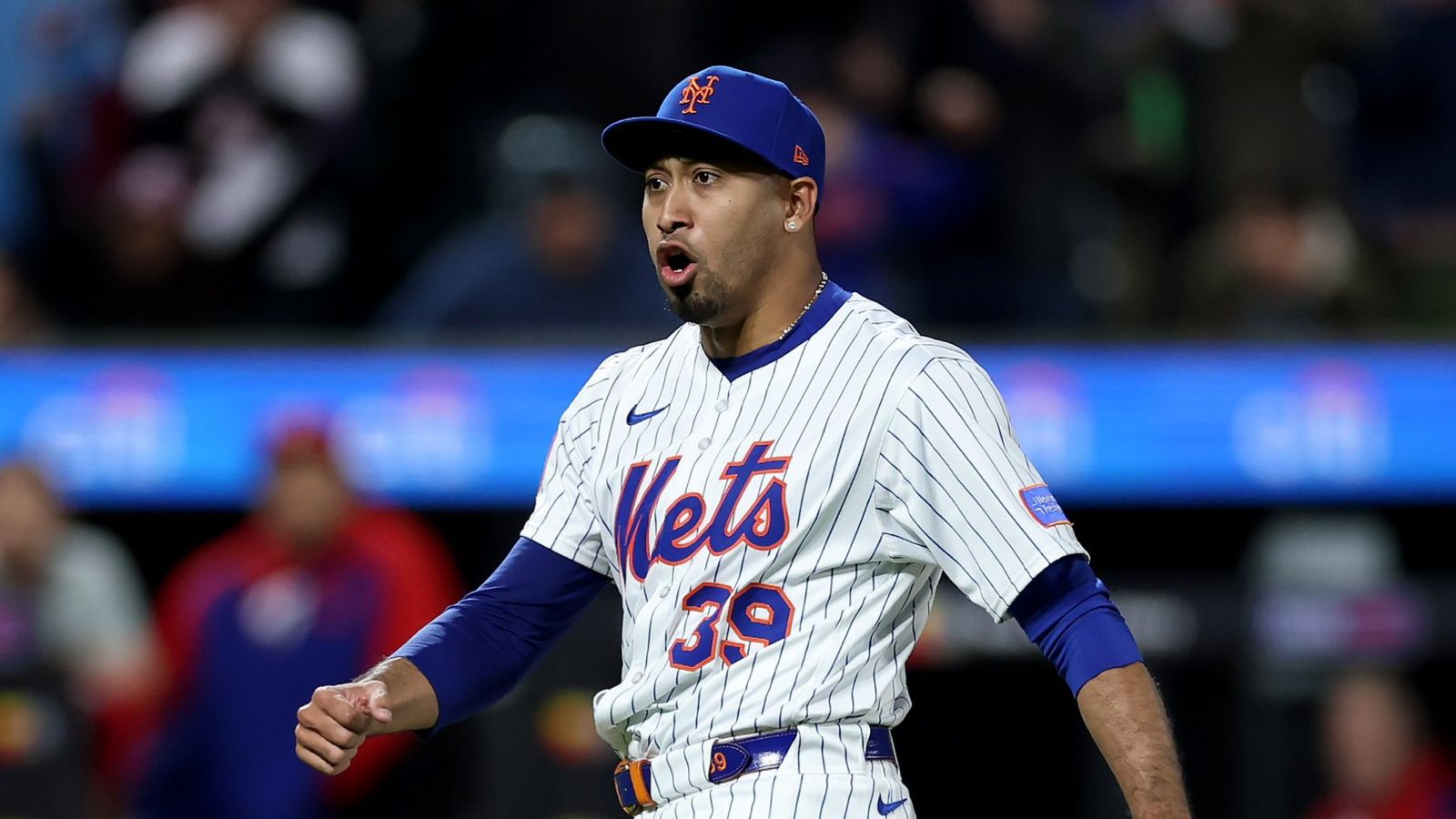 Jugador de beisbol con uniforme en colores blanco, azul y rojo en un estadio durante un juego