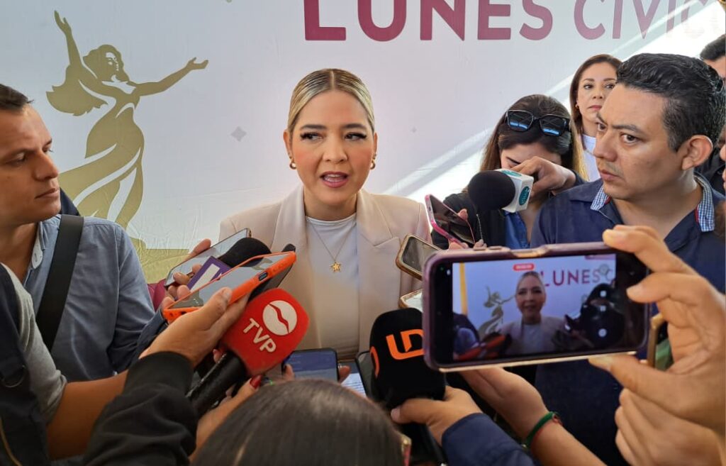 Persona hablando hacia el frente con micrófonos 