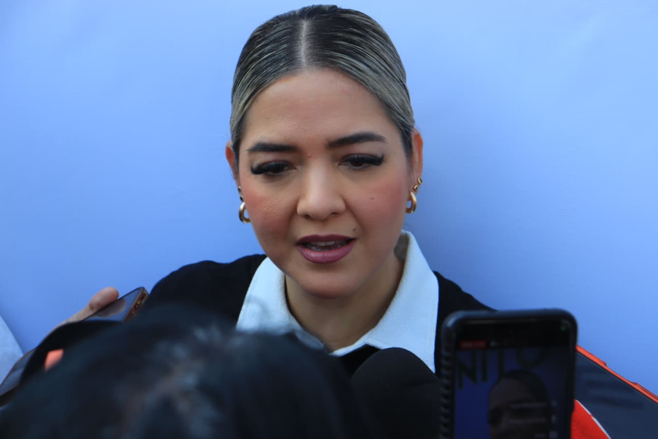 Mujer viendo hacia el frente con micrófonos frente a ella