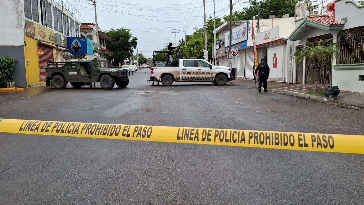 Cinta policial y al fondo unas camionetas del Ejército y la Guardia Nacional